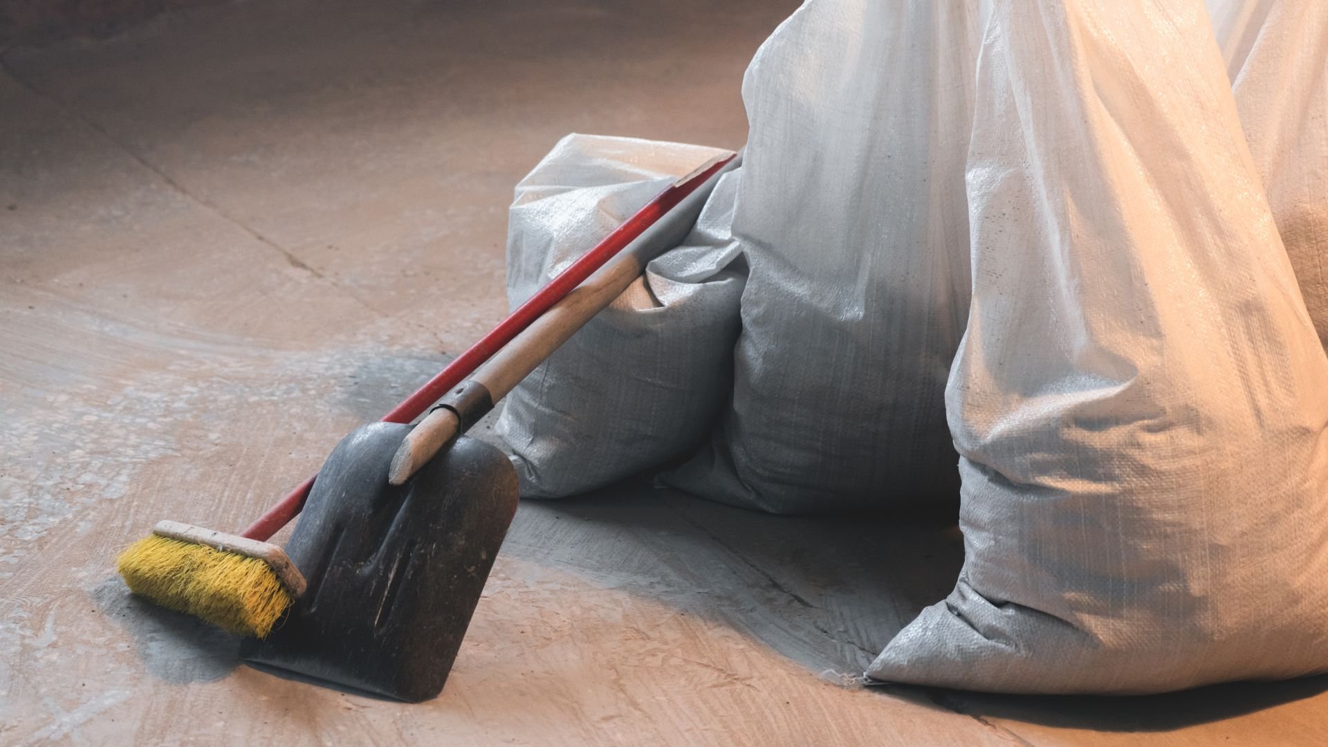 Paint brush and dustpan with gray bags on wooden floor